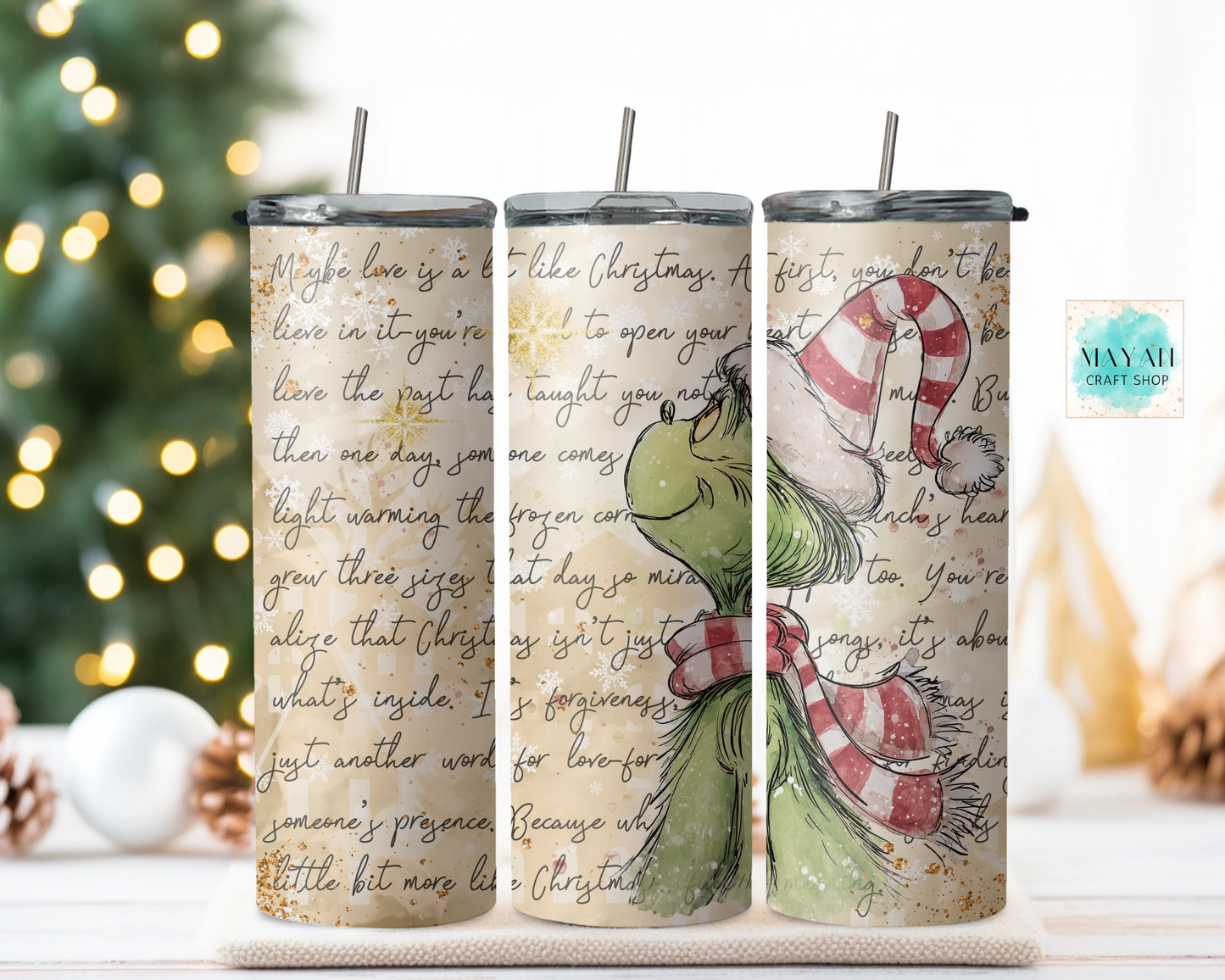 Three tumblers with Christmas-themed designs and text, featuring a green guy illustration, on a decorative background.