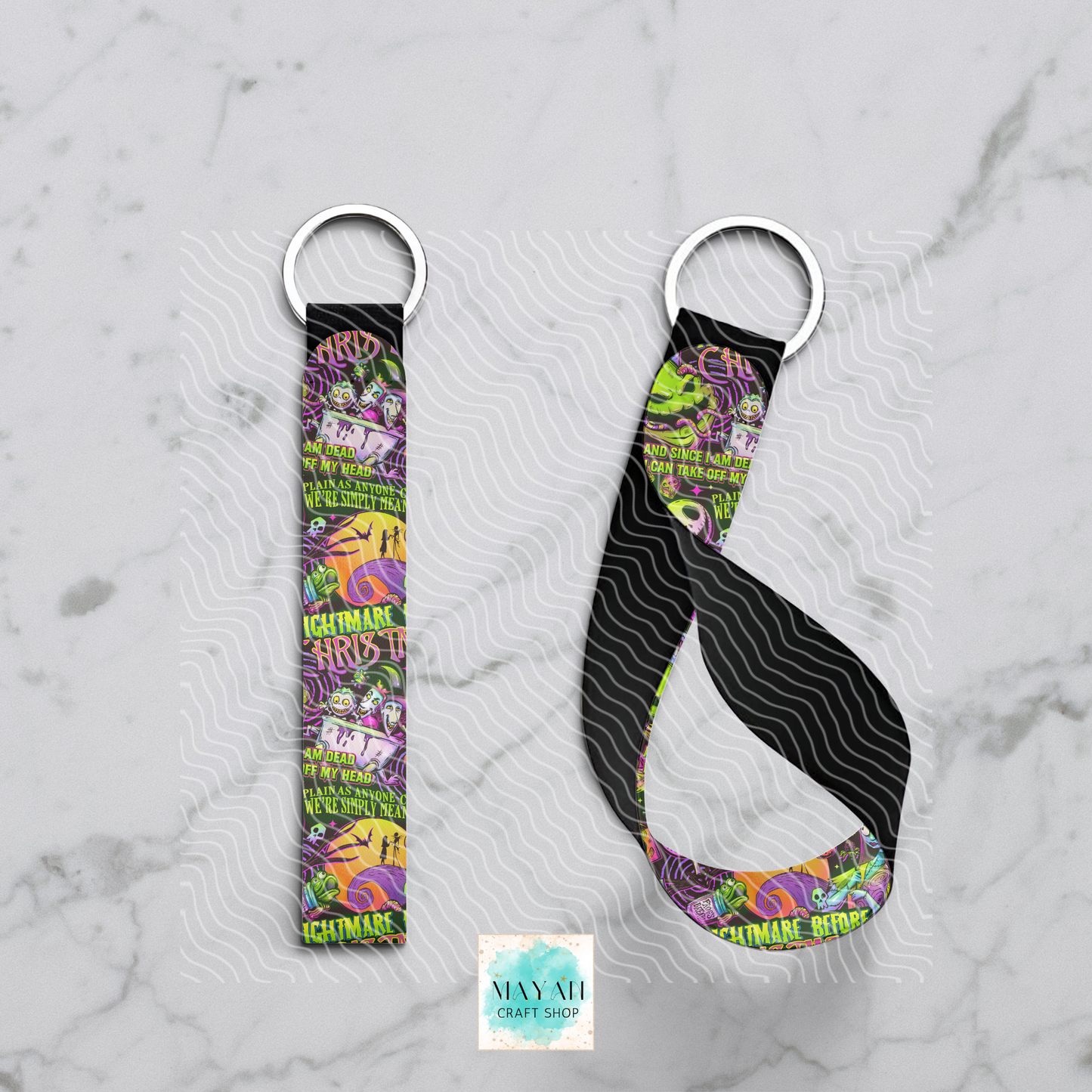Two keychains with colorful designs on a marble surface, featuring the brand 'Mayan Craft Shop'.