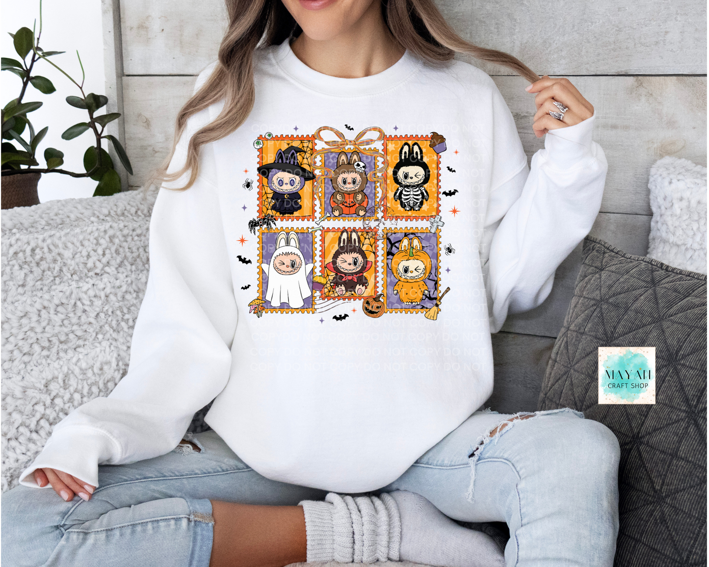 Person wearing a white sweatshirt with Halloween-themed design sitting on a couch.