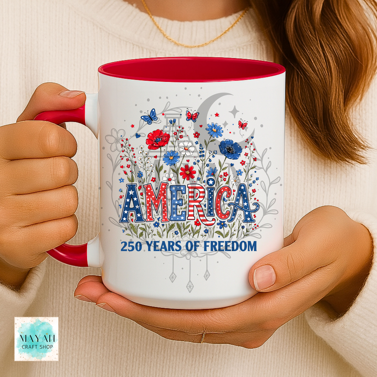 Person holding a mug with 'America 250 Years of Freedom' design and red interior.