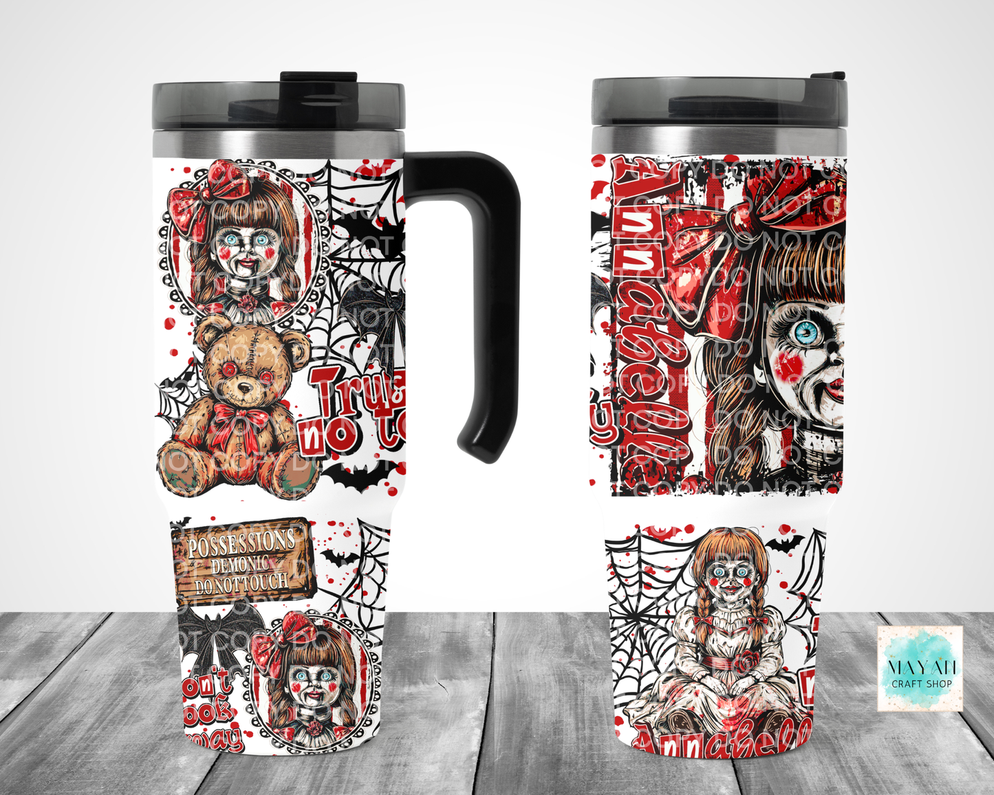 A Halloween-themed travel tumbler mug shown from multiple angles on a gray wood surface against a white background. The mug features a black handle and lid, with a wraparound design in red, black, and white showing a creepy clown doll, spiderwebs, bats.