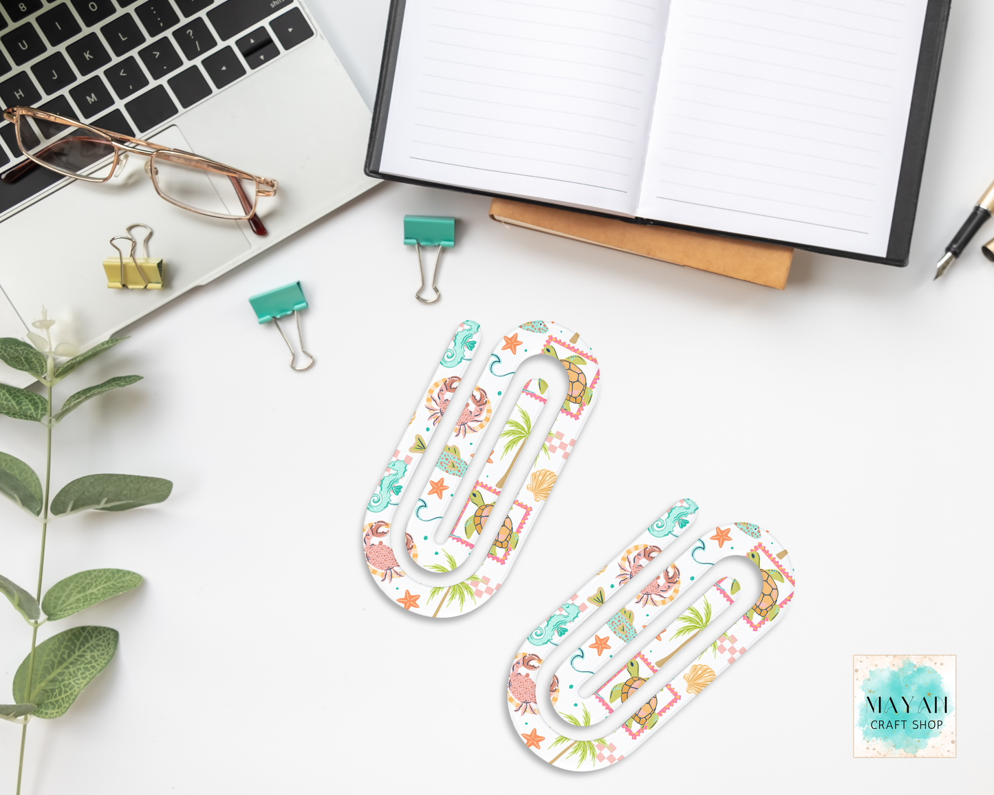 Decorative paper clips on a desk with office supplies and a laptop.