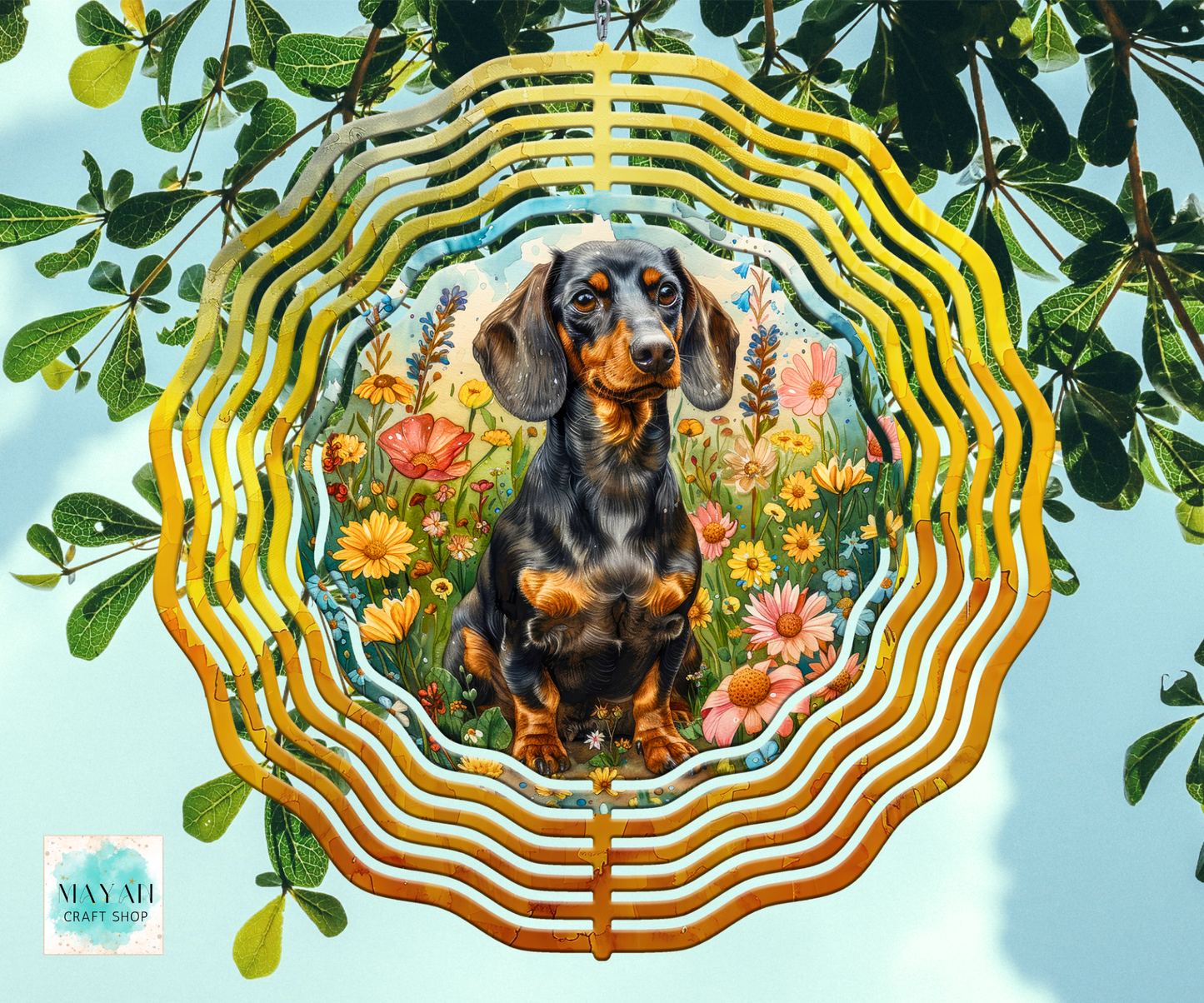 A wind spinner featuring a painted dachshund surrounded by colorful flowers, framed by layered wavy gold and yellow concentric rings, set against a background of green leaves and a light blue sky.