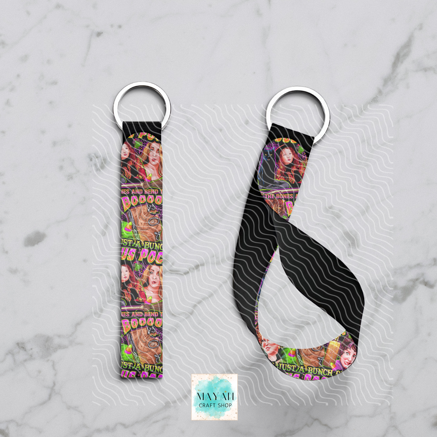 Two keychains with colorful designs on a marble surface, featuring the brand 'Mayan Craft Shop'.
