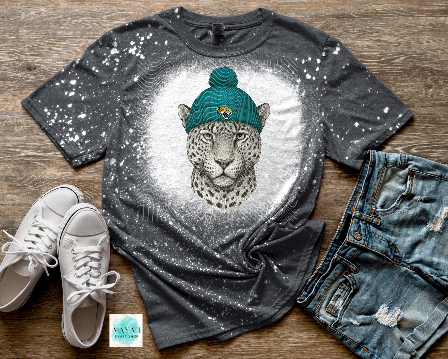 Gray t-shirt with a leopard graphic wearing a blue beanie, paired with white sneakers and jeans on a wooden surface.