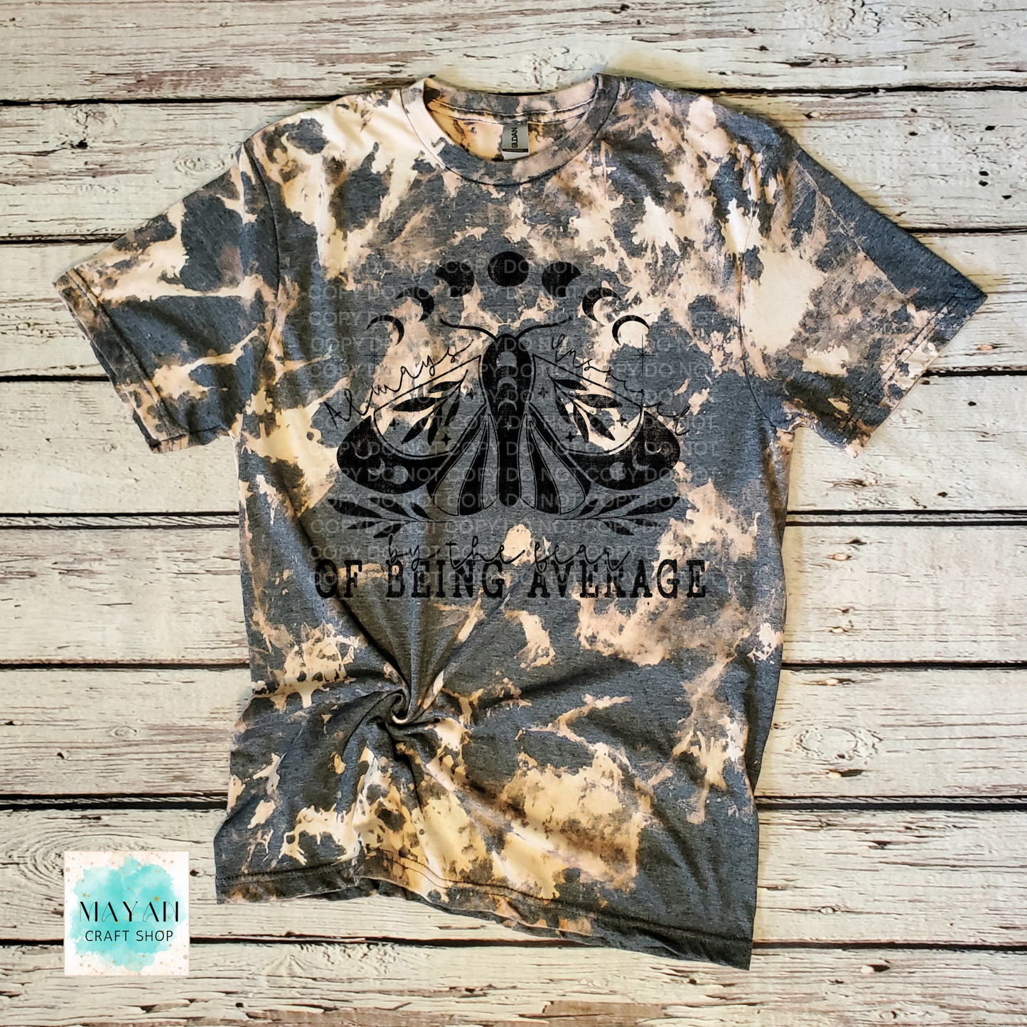 Bleached t-shirt with butterfly design and text on a wooden surface