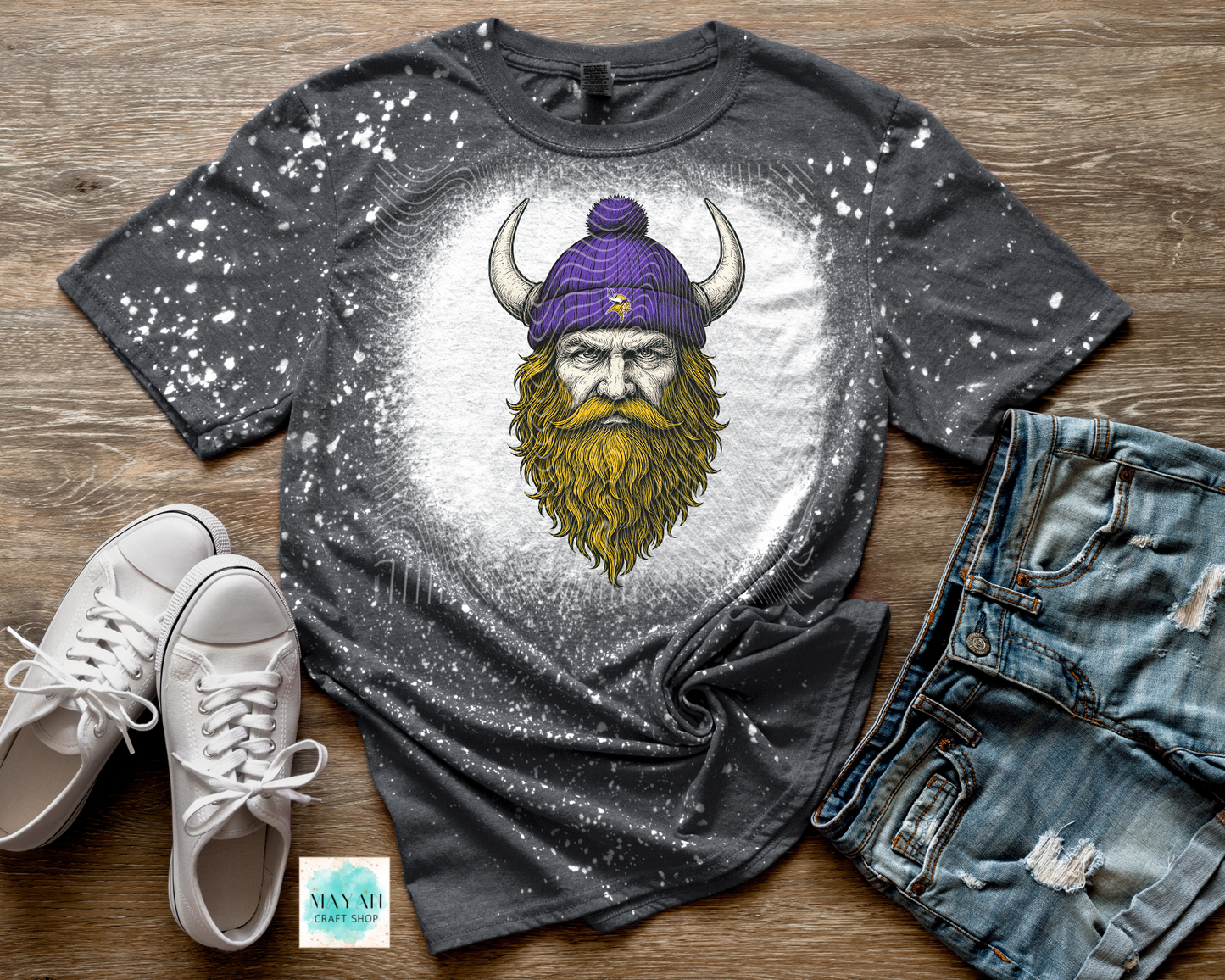 Gray t-shirt with a Viking graphic on a wooden surface with shoes and jeans.