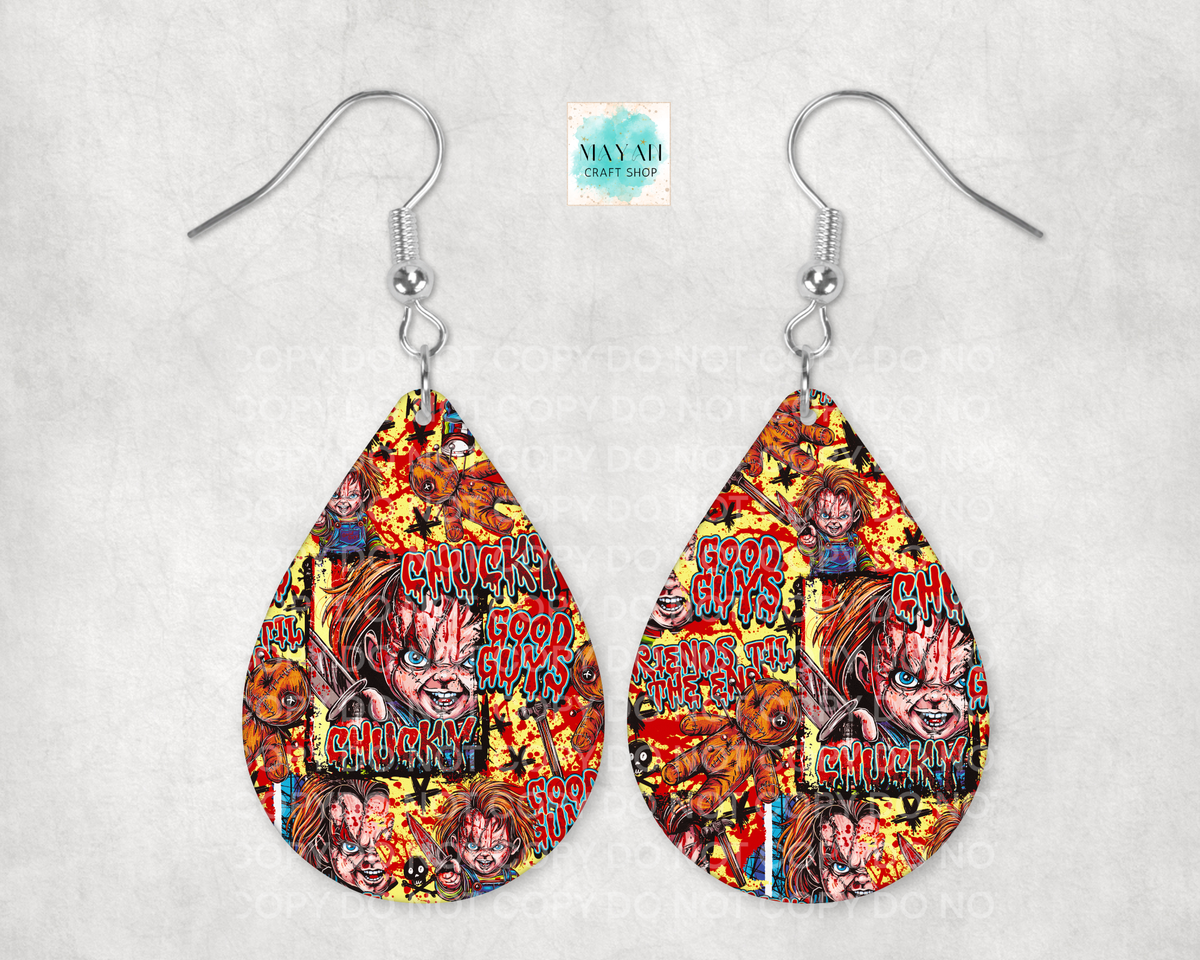 A pair of teardrop-shaped dangle earrings with silver fishhook wires, featuring a colorful comic-style collage print with horror character faces and words. The earrings are displayed against a light gray textured background.