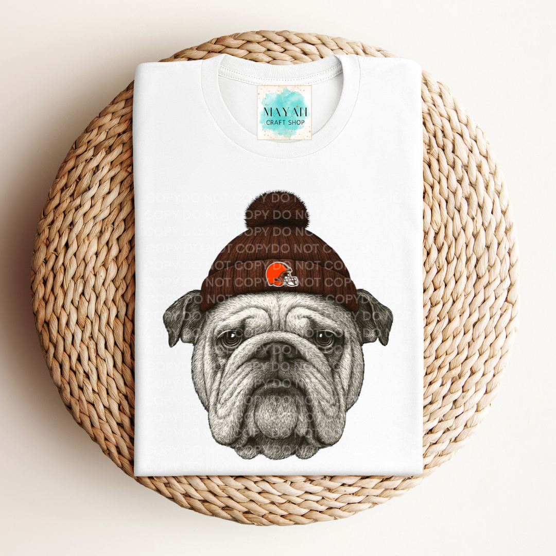 White t-shirt with a graphic of a bulldog wearing a beanie on a woven mat