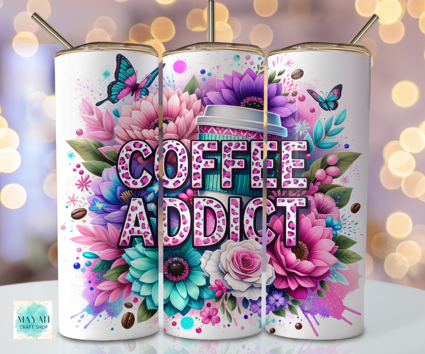 Three colorful tumblers with floral designs and 'Coffee Addict' text on a blurred bokeh background.