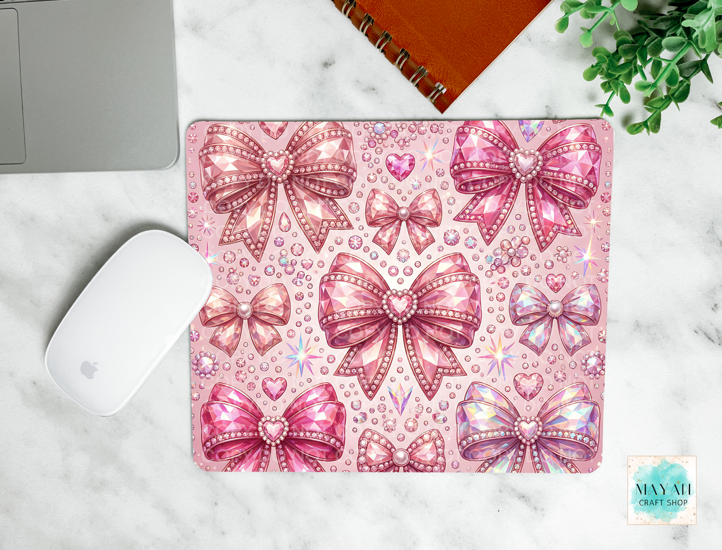 Pink bow patterned mouse pad on a marble surface with a laptop and mouse.