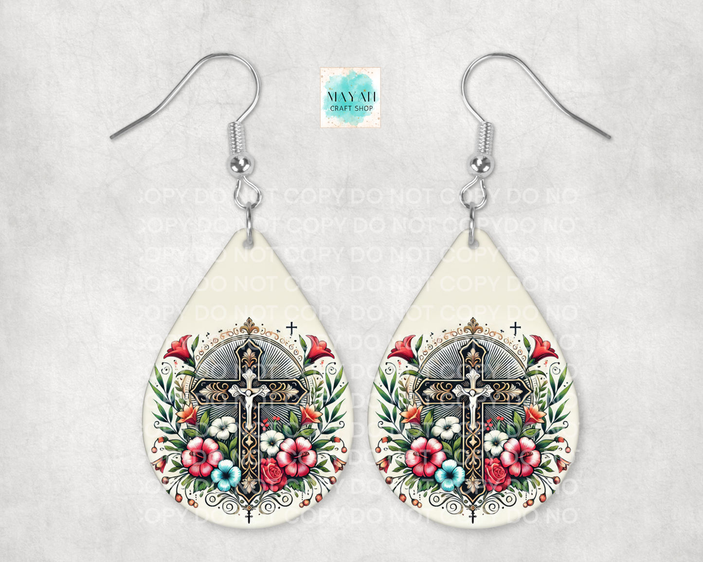Teardrop-shaped earrings with floral and cross design on a light gray background