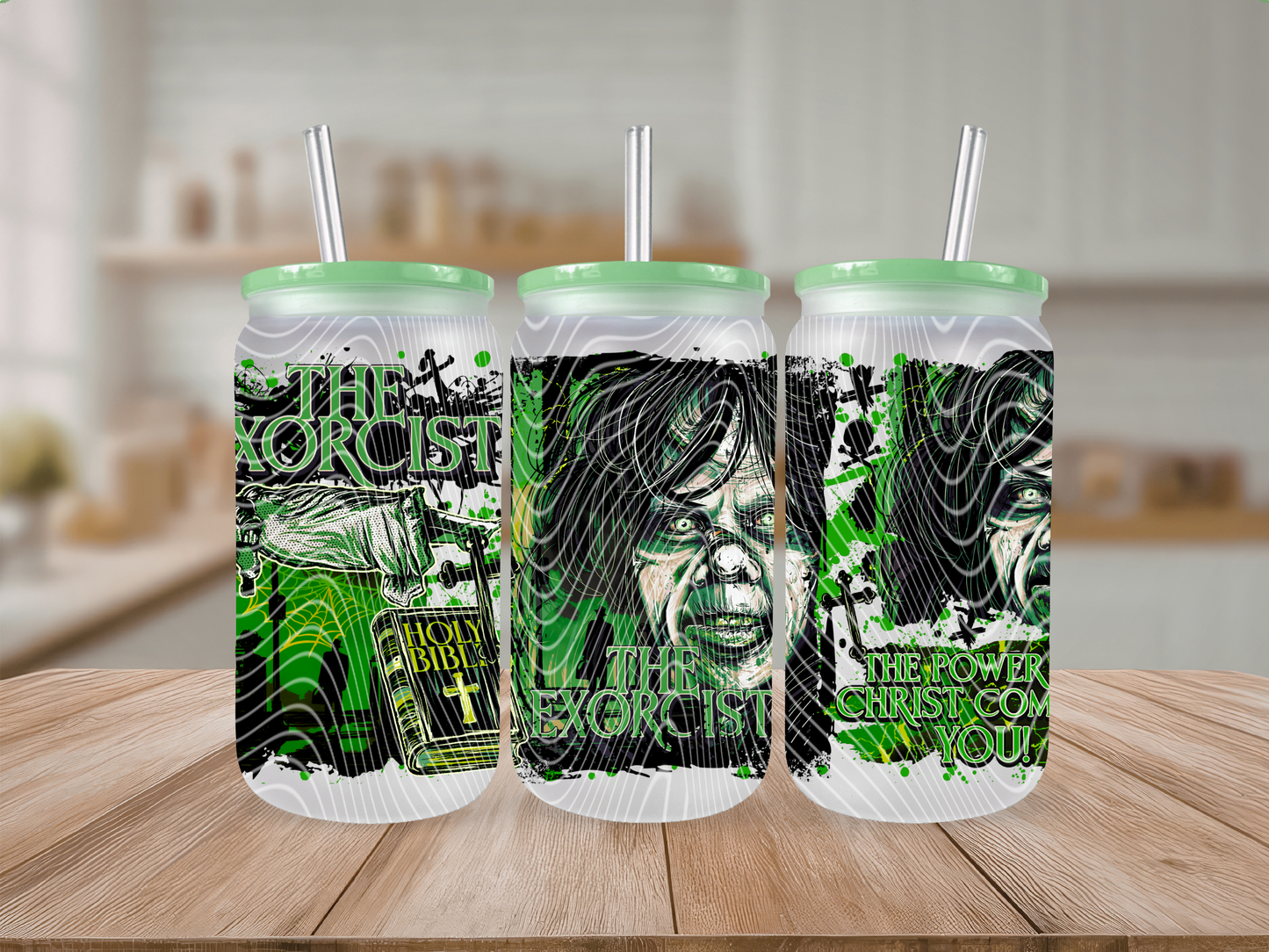 Three tall frosted tumblers with mint green lids and straws, printed with green and black horror-themed artwork and text, displayed on a wooden surface against a blurred kitchen background.