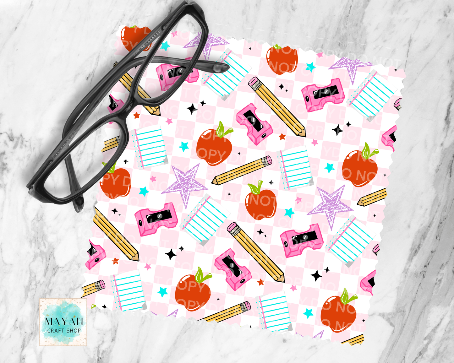 Pink patterned paper with school-themed stickers and a pair of glasses on a marble surface.