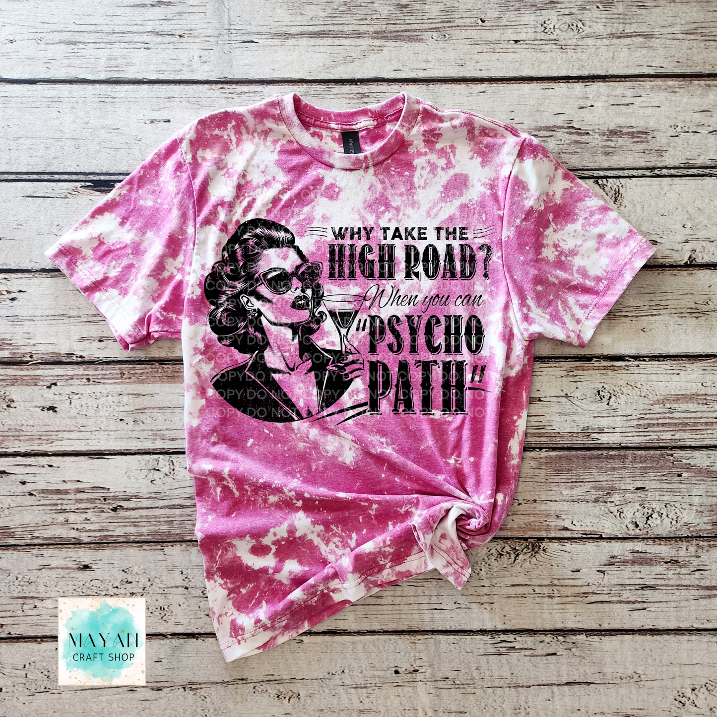 Pink tie-dye t-shirt with graphic design and text on a wooden surface