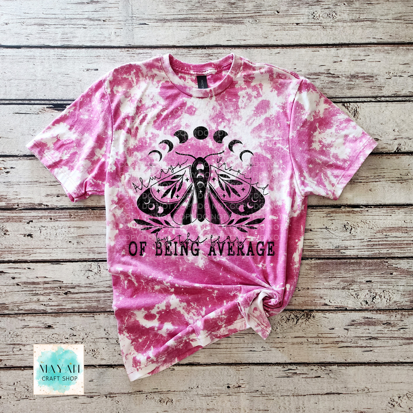 Pink tie-dye t-shirt with black butterfly design and text on a wooden surface