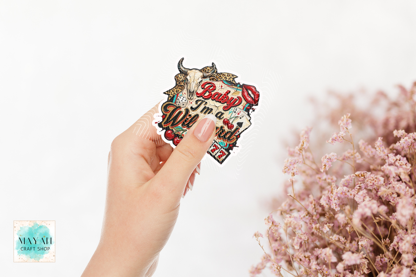 Hand holding a 'Baby I'm Well' card with decorative elements on a white background