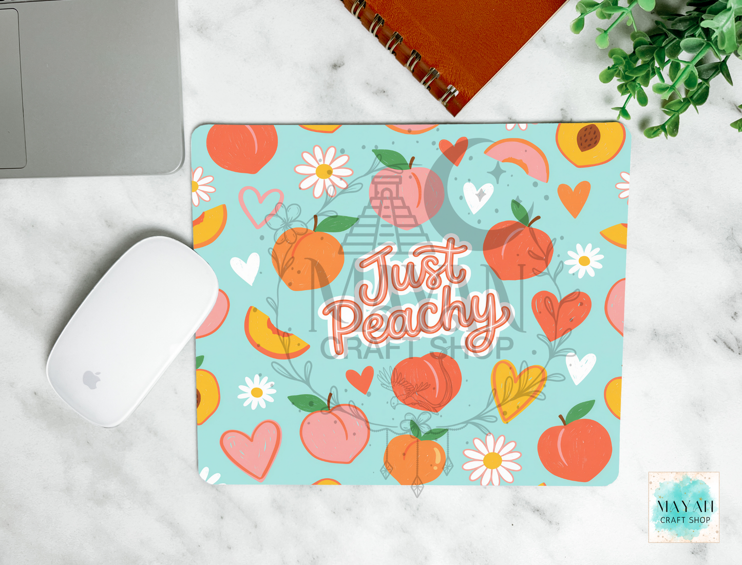 Mouse pad with peach design and 'Just Peachy' text on a marble surface.