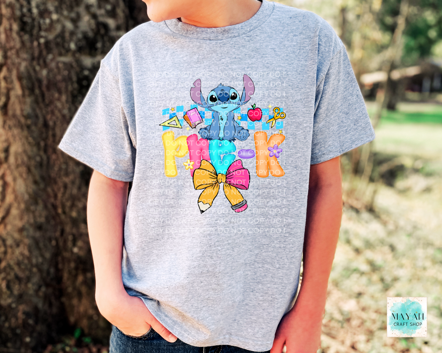 Child wearing a gray t-shirt with colorful character design and text outdoors.