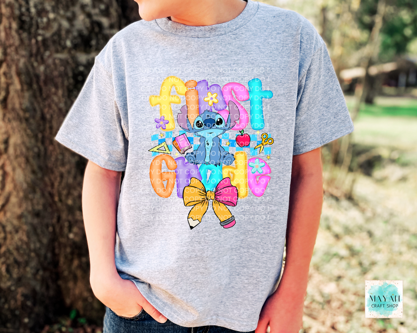 Child wearing a gray t-shirt with colorful graphics and text, standing outdoors.