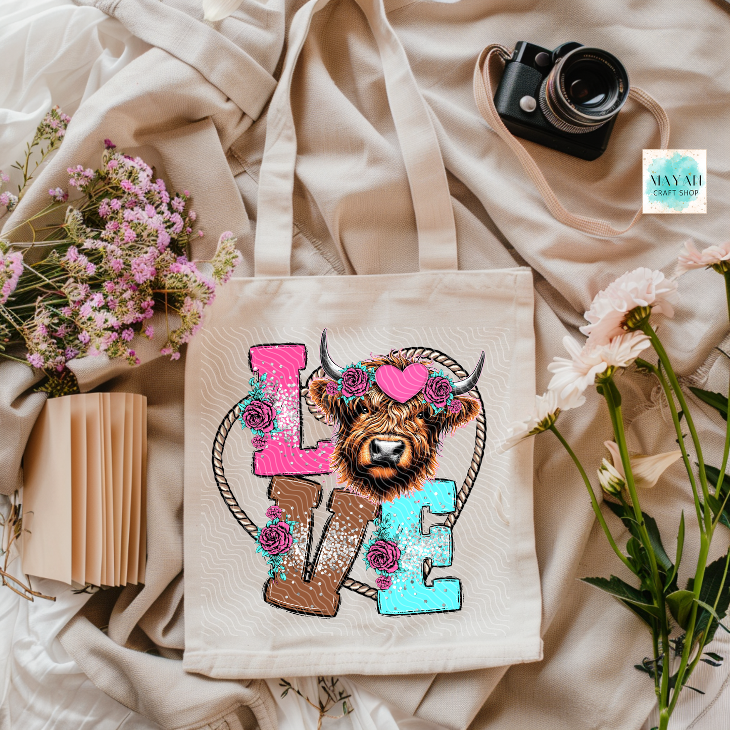 Tote bag with a cow design and 'LOVE' letters on a soft fabric background.