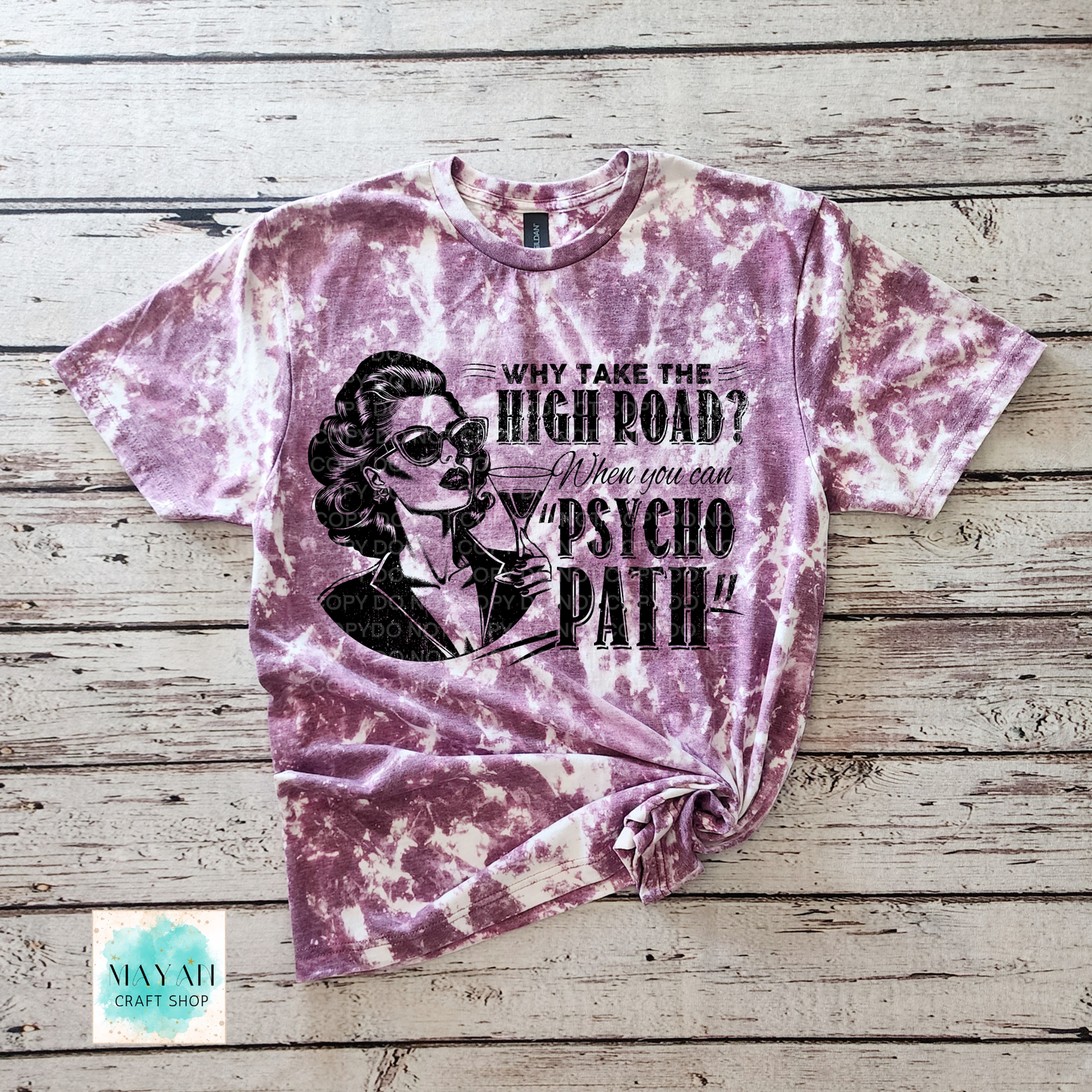Tie-dye t-shirt with graphic design and text on a wooden surface, featuring the brand 'Mayan Craft Shop'.
