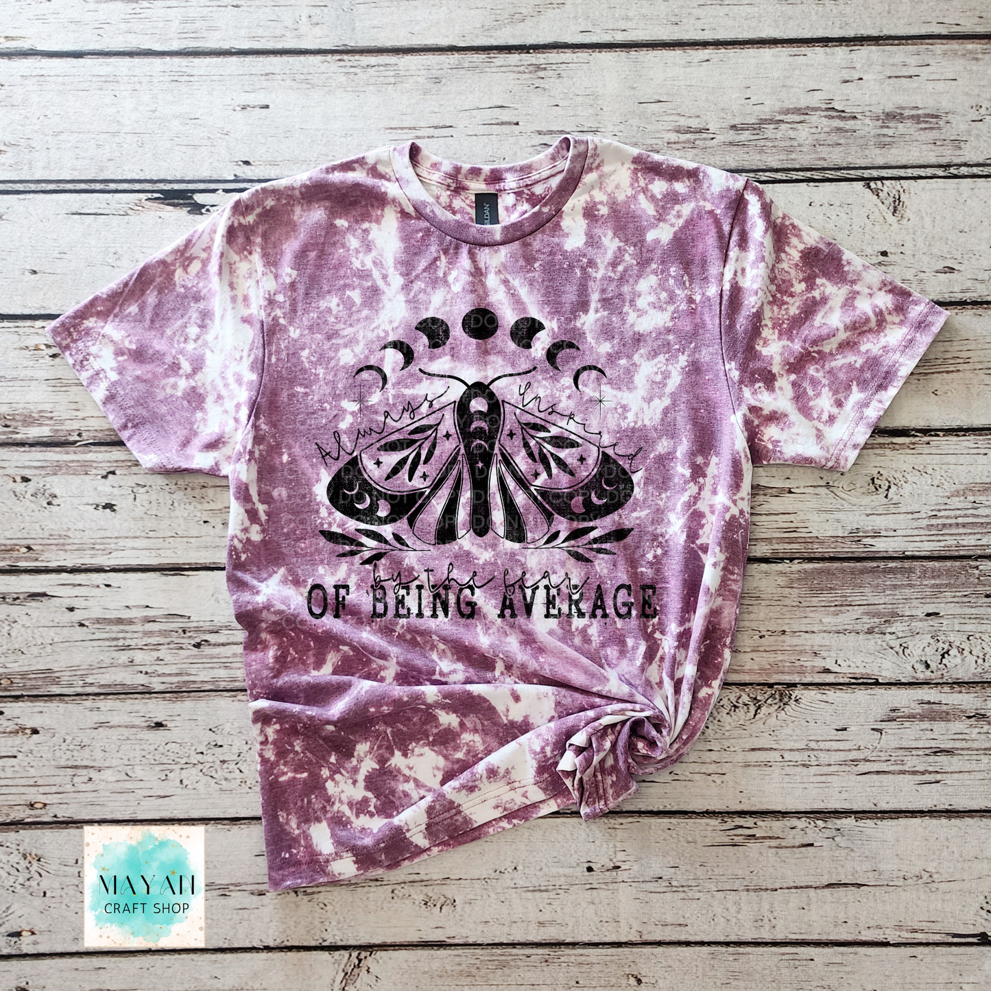 Tie-dye t-shirt with a butterfly graphic and text on a wooden surface, branded 'Mayan Craft Shop'.