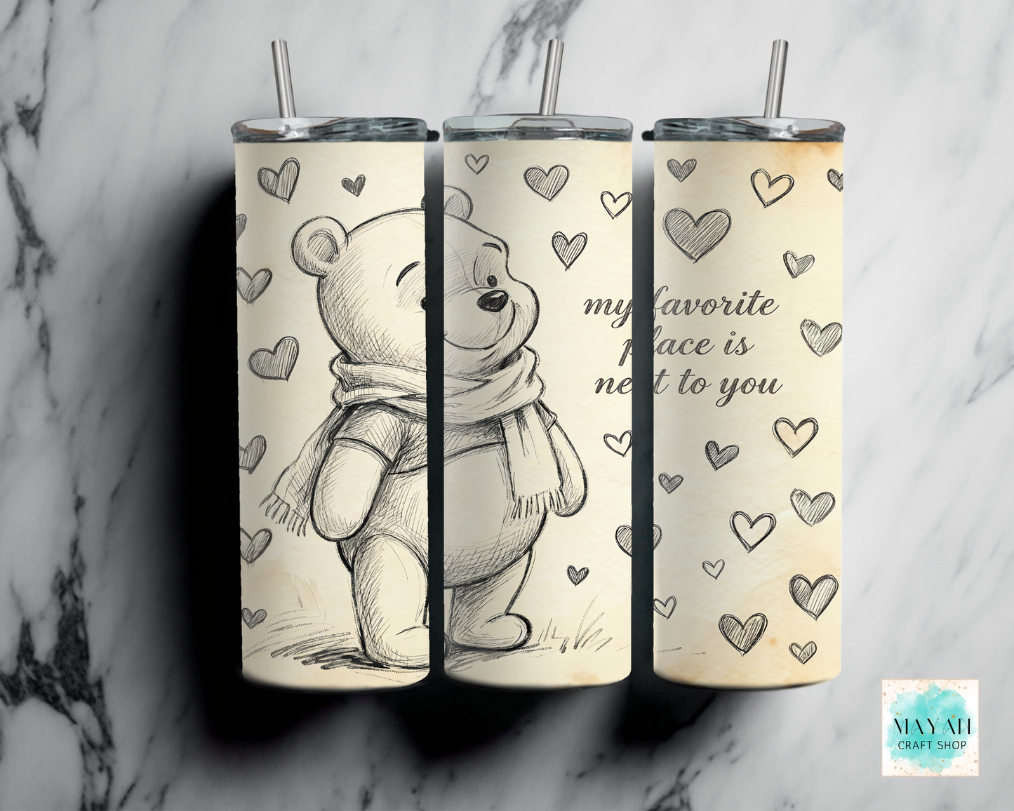 Three tumblers with a bear design and heart patterns on a marble background