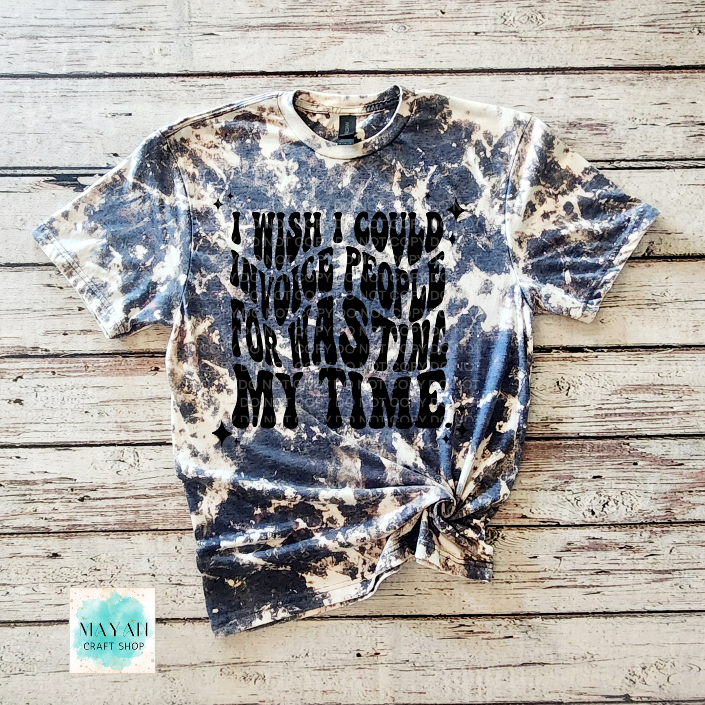 Tie-dye t-shirt with text on a wooden surface, branded 'Mayan Craft Shop'.