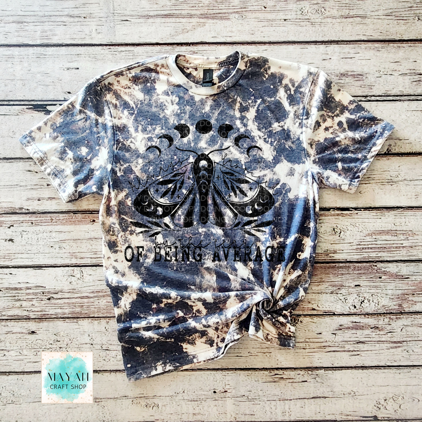 Bleached t-shirt with moth design and 'Of Being Average' text on a wooden surface, Mayan Craft Shop.