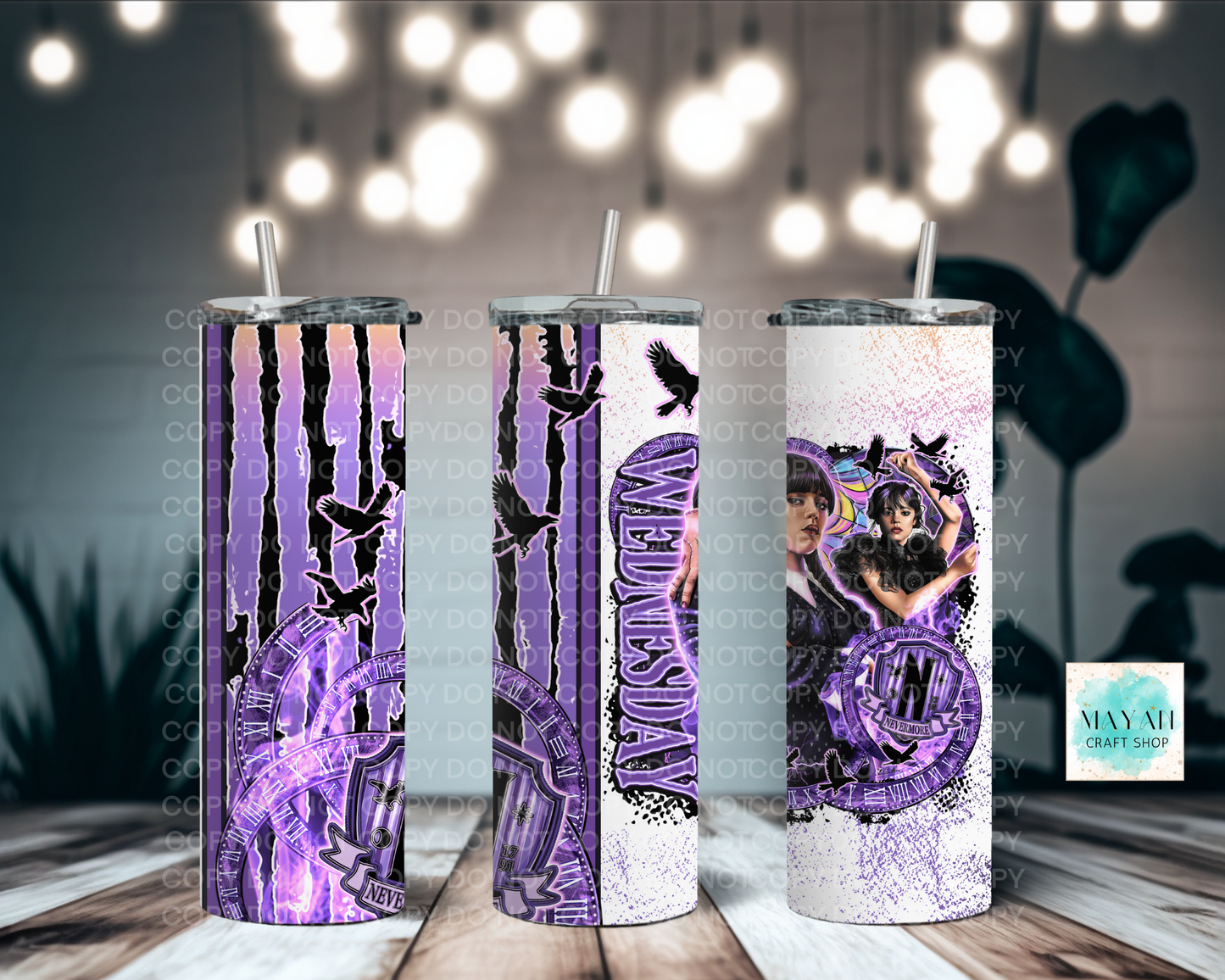 Three purple-themed tumbler with designs on a wooden surface with blurred lights in the background.