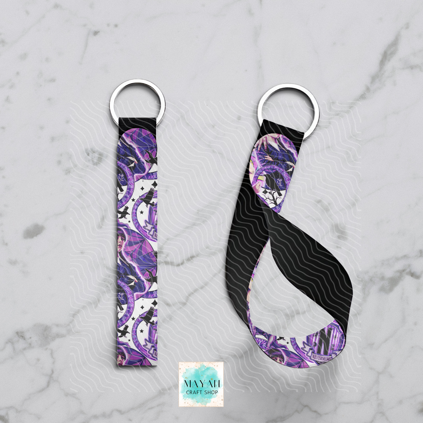 Two keychains with purple and black pattern on a marble surface.