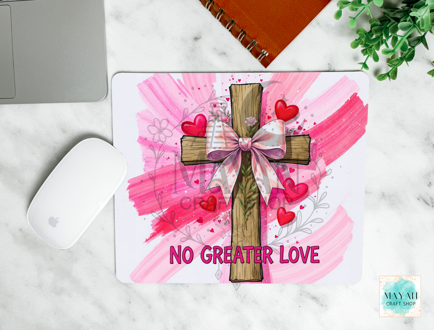 Mouse pad with a cross design, hearts, and 'No Greater Love' text on a marble surface.