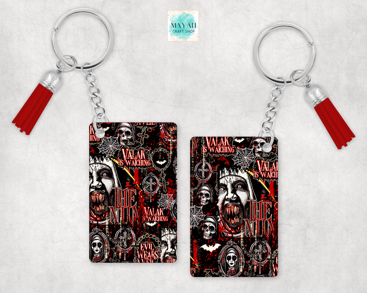 Two keychains with red tassels, featuring a gothic theme with skulls, teeth, and words on a light gray textured background.