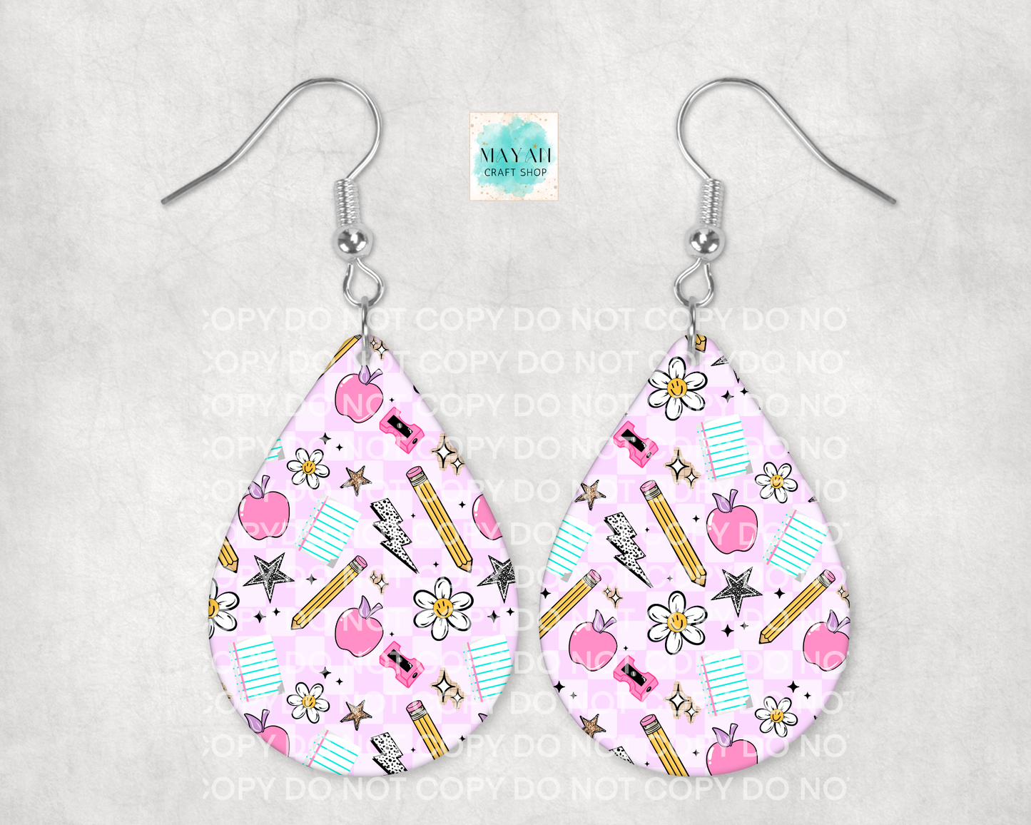 Teardrop-shaped earrings with a pink pattern featuring apples, pencils, and flowers on a gray background.