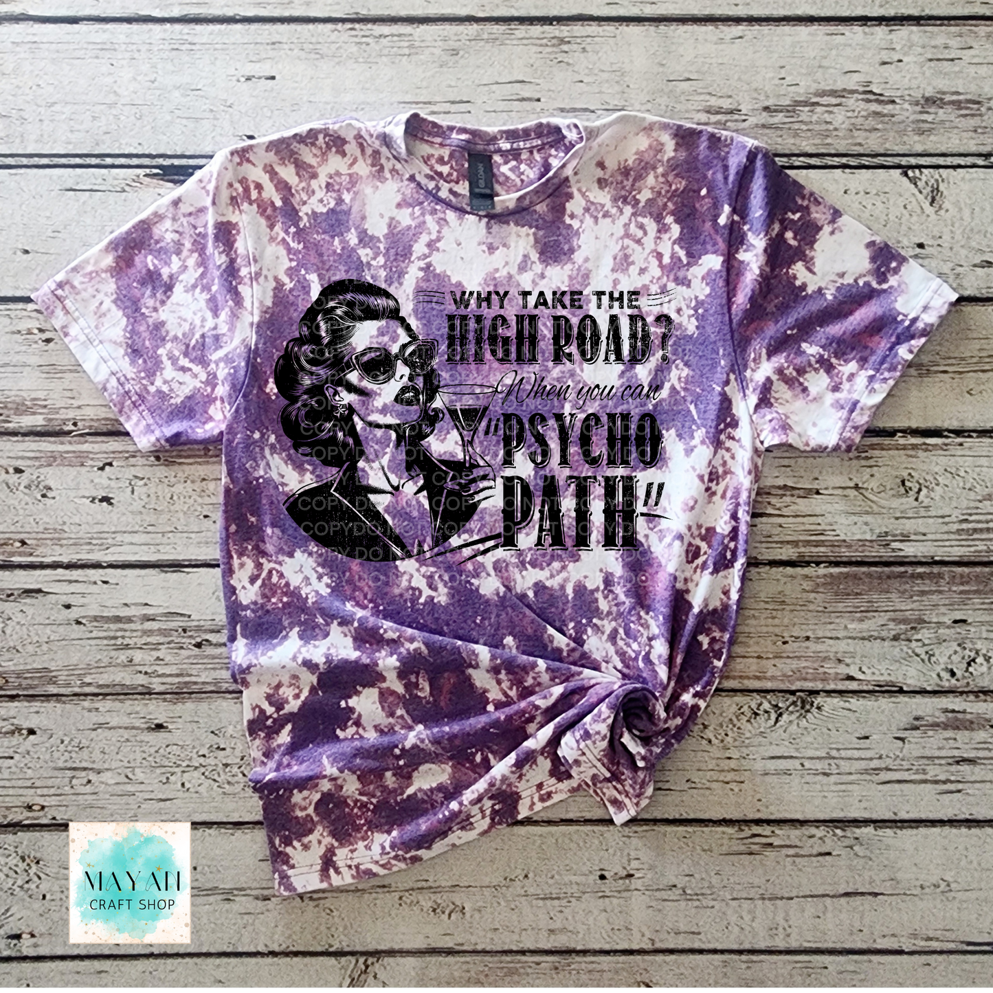 Purple tie-dye t-shirt with graphic design and text on a wooden surface