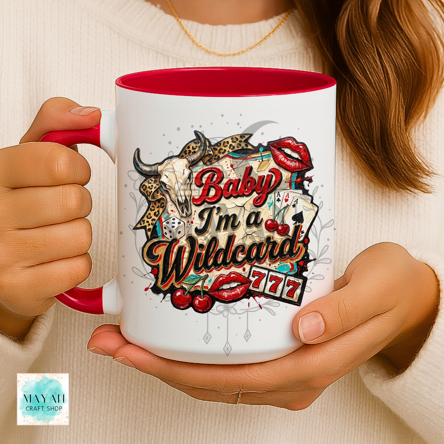 Person holding a mug with a colorful design and text, featuring a red interior.