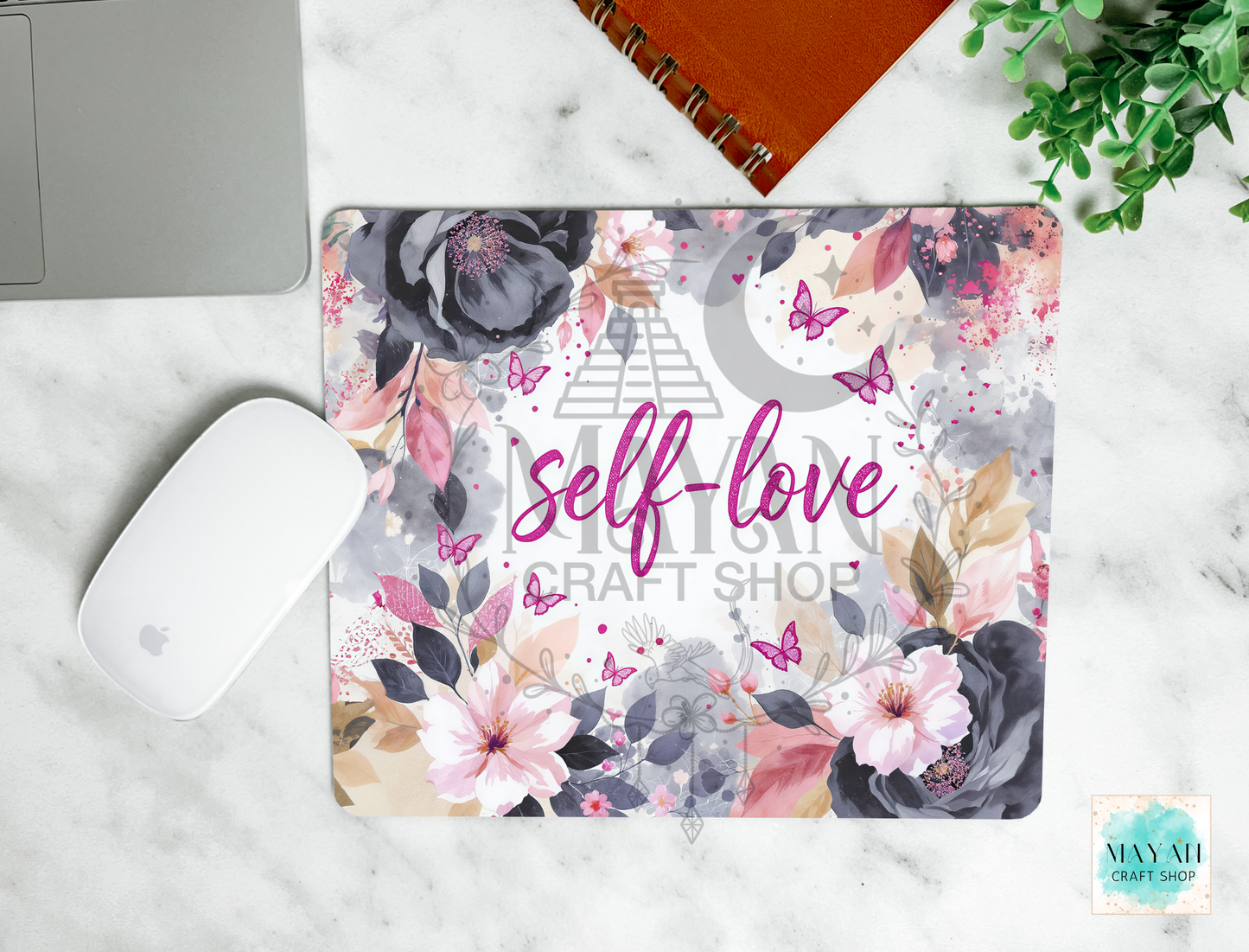 Floral mouse pad with 'self-love' text on a marble surface