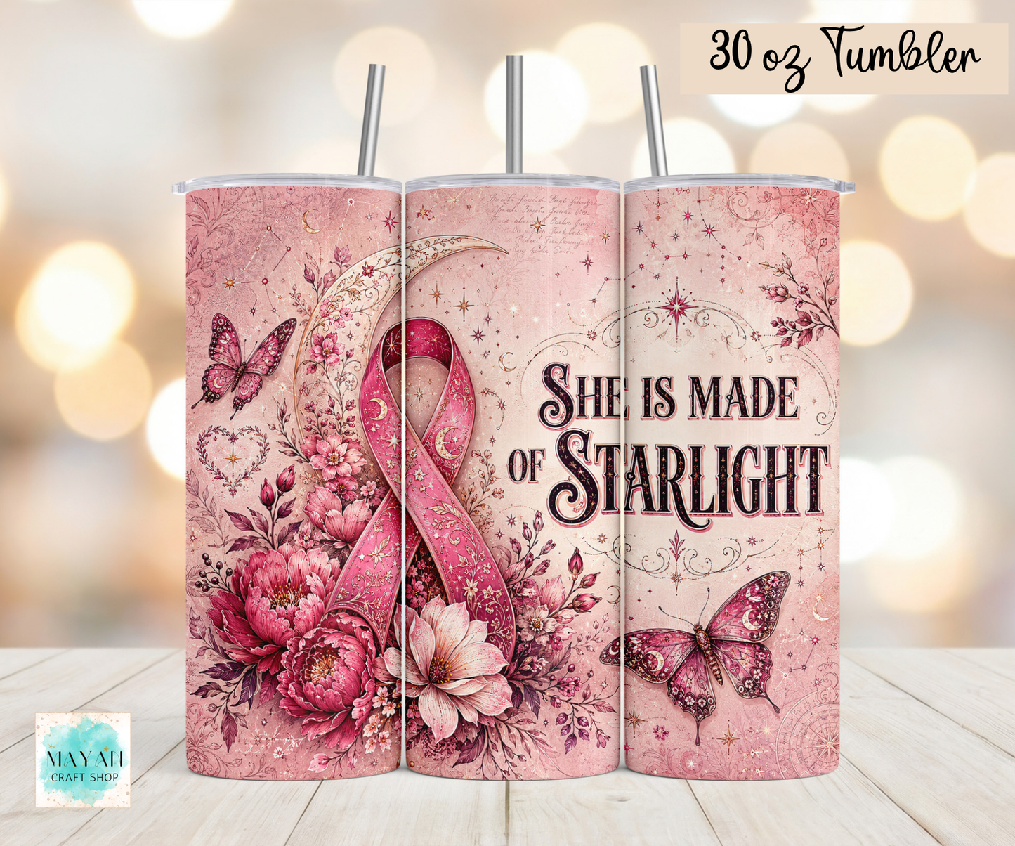 Three views of a 30 oz stainless steel tumbler with a pink floral and ribbon design, featuring the text 'She Is Made Of Starlight' and butterflies, shown on a wooden surface with a warm bokeh background.