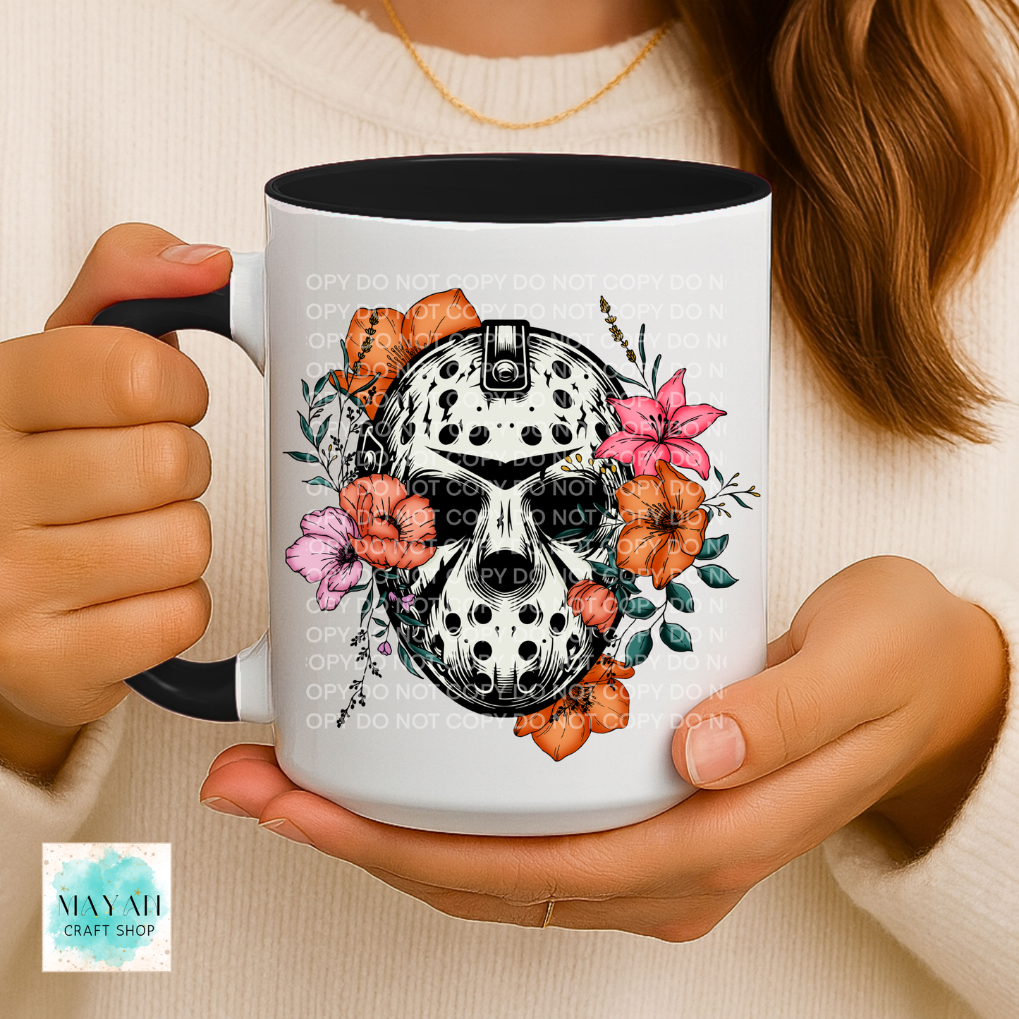 Person holding a mug with a skull and floral design.