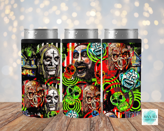 Three slim can coolers with silver aluminum can tops, featuring a vibrant, multi-colored Halloween collage print of skulls, clowns, and ghosts on a black background, displayed on a wooden surface with a soft bokeh light background.