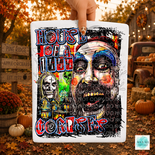 A rectangular white shirt featuring a colorful horror-themed graphic and illustrated faces, held by a hand against an autumn outdoor backdrop with pumpkins and fall foliage.