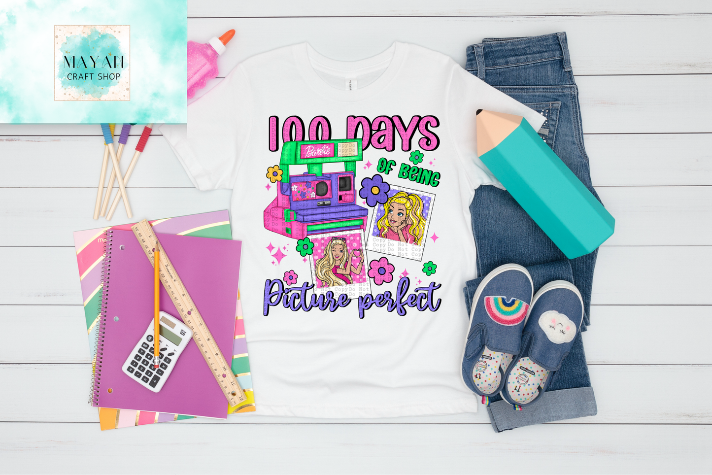 100 Days of School themed shirt with school supplies on a wooden surface