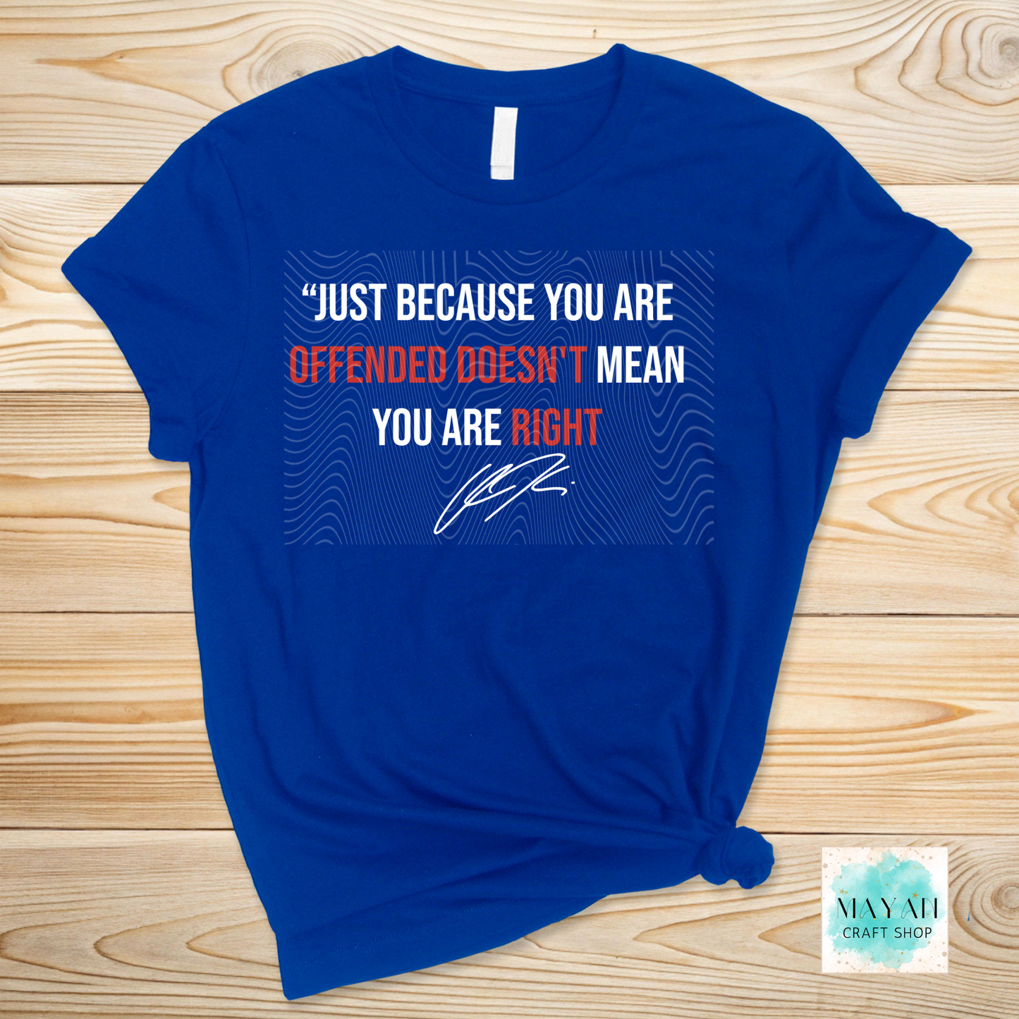 Blue t-shirt with a printed message on a wooden surface.