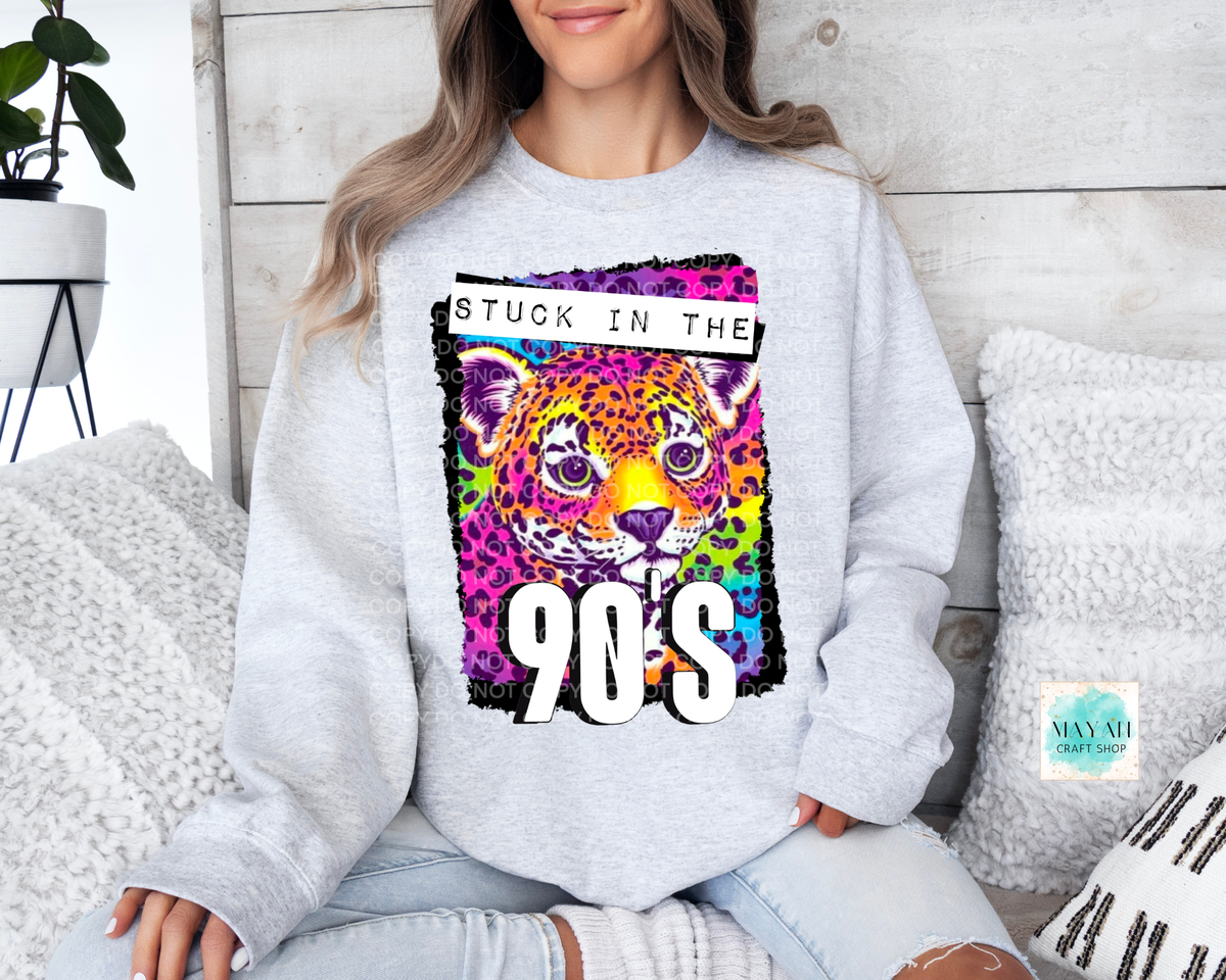A woman wearing a light gray sweatshirt with a colorful graphic of a leopard and the text 'STUCK IN THE 90S'.