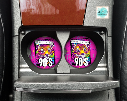 Two circular car cup holders featuring a colorful graphic of a leopard with the text 'STUCK IN THE 90'S' and a pink background, installed in a car's center console.