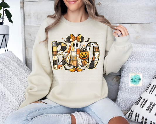 Person wearing a cream sweatshirt with Halloween-themed design sitting on a couch.
