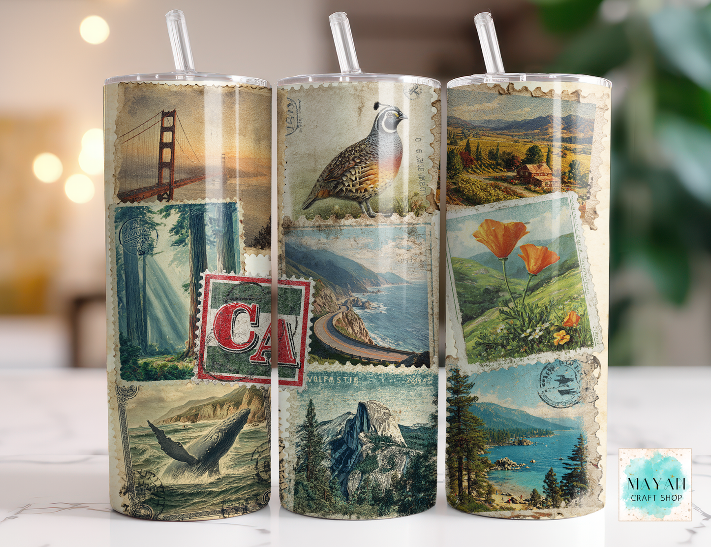 Three cylindrical tumbler with scenic designs on a white surface.