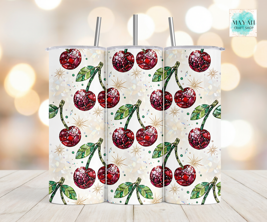 Three cherry-patterned tumblers on a light wooden surface with a blurred background.