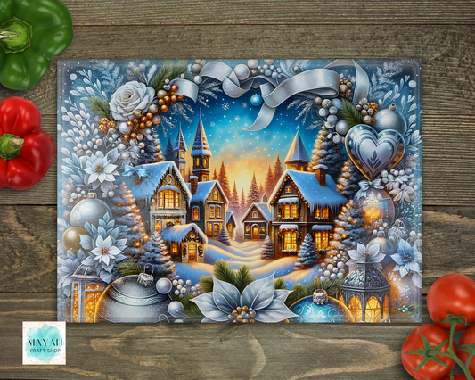 Decorative cutting board with a winter village scene, surrounded by vegetables on a wooden surface.